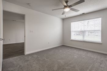 an empty living room with a large window and a ceiling fan at Latitudes Apartments, Indianapolis